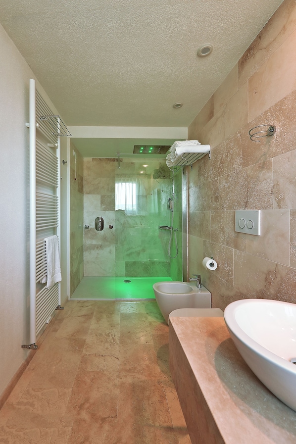 A modern bathroom with a glass-enclosed shower, a white sink, and a towel rack. - Relais Val d'Orcia (Pienza)