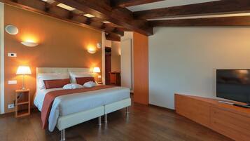 Un dormitorio moderno con una cama grande, vigas de madera, un televisor y un armario de madera.