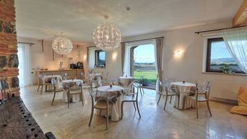 A dining area with round tables and chairs, a brick wall, and a view of the outdoors.