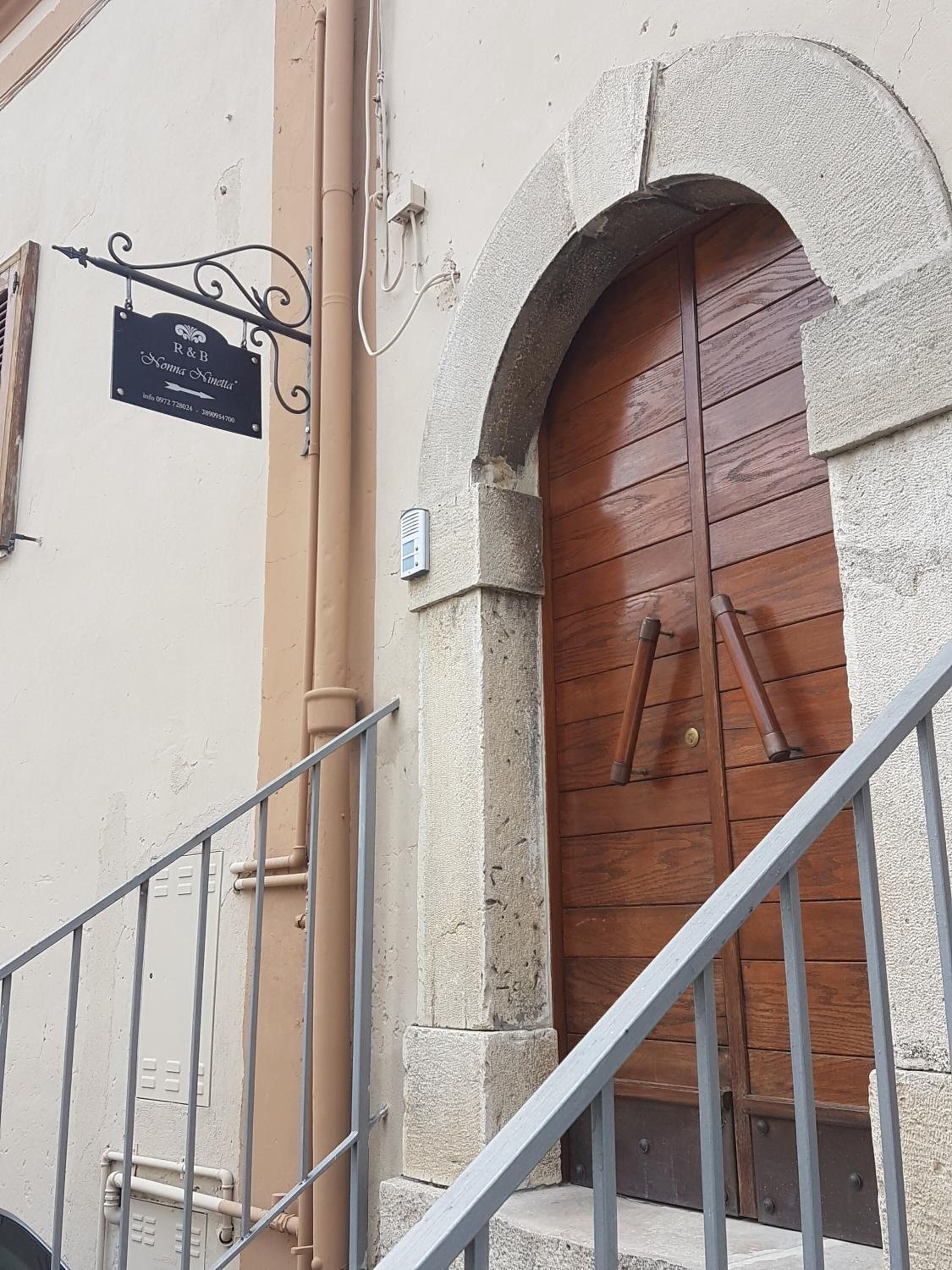 Une entrée d’immeuble avec une porte en bois, un escalier en métal et une enseigne au-dessus de la porte.