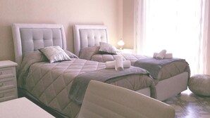Una habitación de hotel con dos camas, una mesita de noche y una silla.