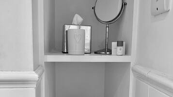 A bathroom with a mirror, a tissue box, a small bottle, a pitcher, and essential oils on a tray.