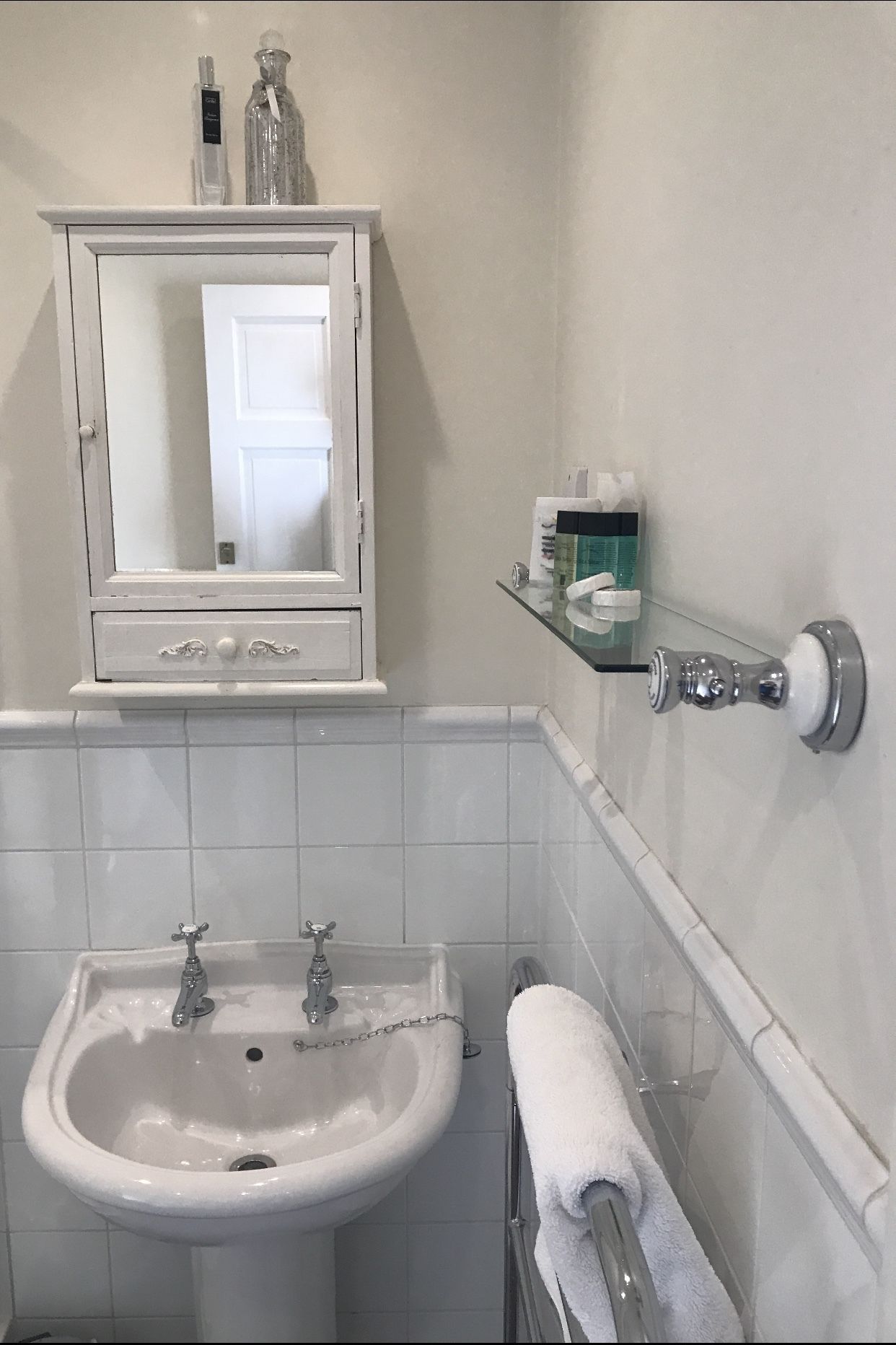 A bathroom with a white sink, a mirror above it, and a towel rack with a towel.