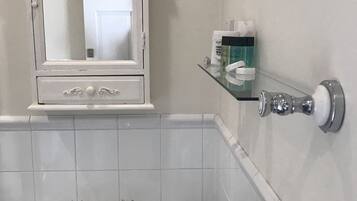 A bathroom with a white sink, a mirror above it, and a towel rack with a towel.