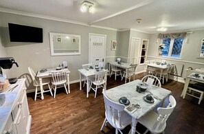 Enjoy meals in a classic dining area with a traditional layout, featuring tables, chairs, and a flat-screen TV.