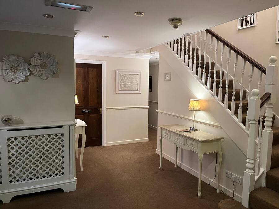 A hallway with a staircase, a white console table, and a door labeled "The Great Park".