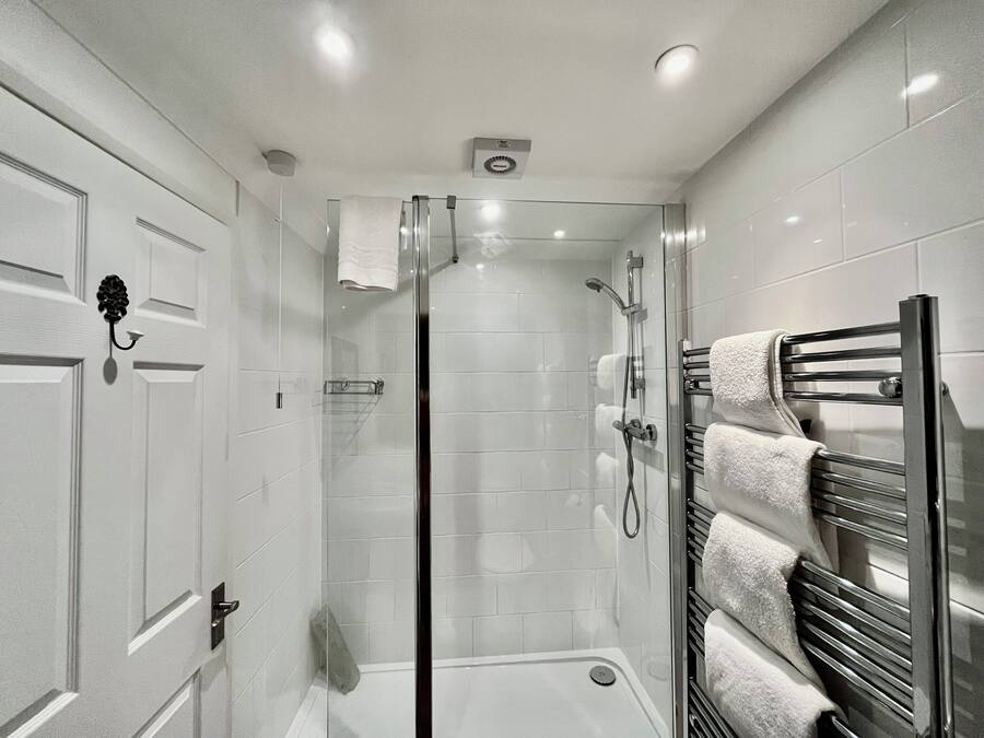 A modern bathroom with a glass-enclosed shower, a glass door, and a towel rack with multiple towels.