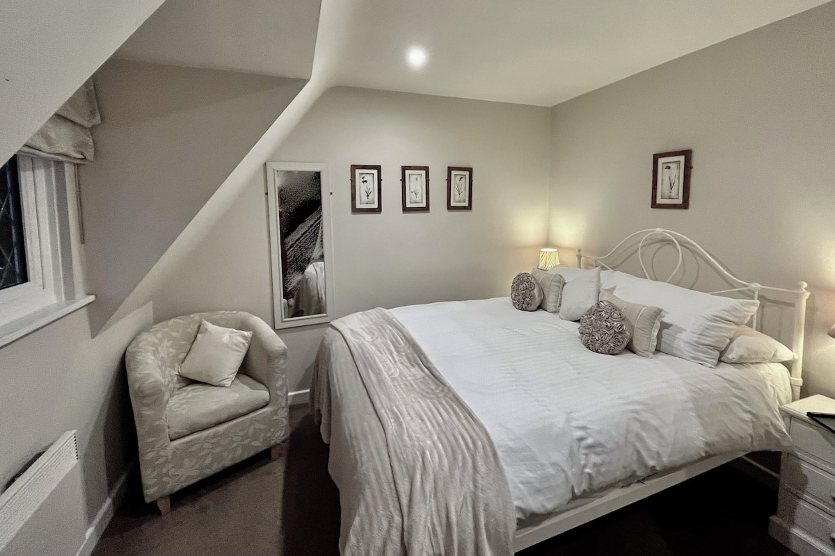 A bedroom with a bed, a chair, a nightstand, and framed pictures on the wall.