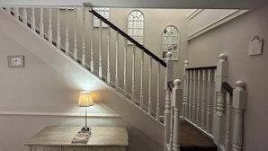 A staircase with white balusters and a dark handrail, leading to a landing with a table and lamp. - Park Farm Bed and Breakfast (Windsor)