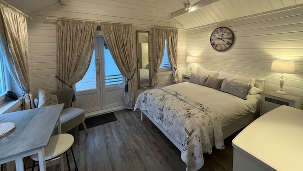 A cozy bedroom with a bed, bedside tables, a clock, and a window with curtains. - Park Farm Bed and Breakfast (Windsor)