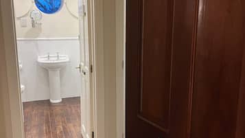 Un baño con lavamanos, inodoro y espejo con ventanal circular.