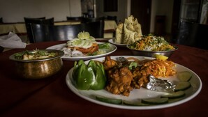 Una mesa de comedor con varios platos, incluyendo un pimiento verde, un plato de pollo y un tazón de arroz.