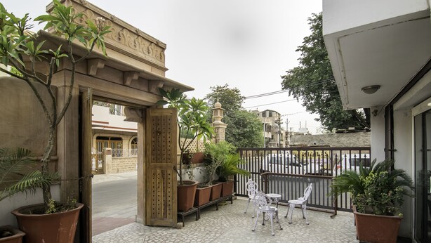 Un patio con suelo de baldosas, plantas en macetas y mobiliario exterior.