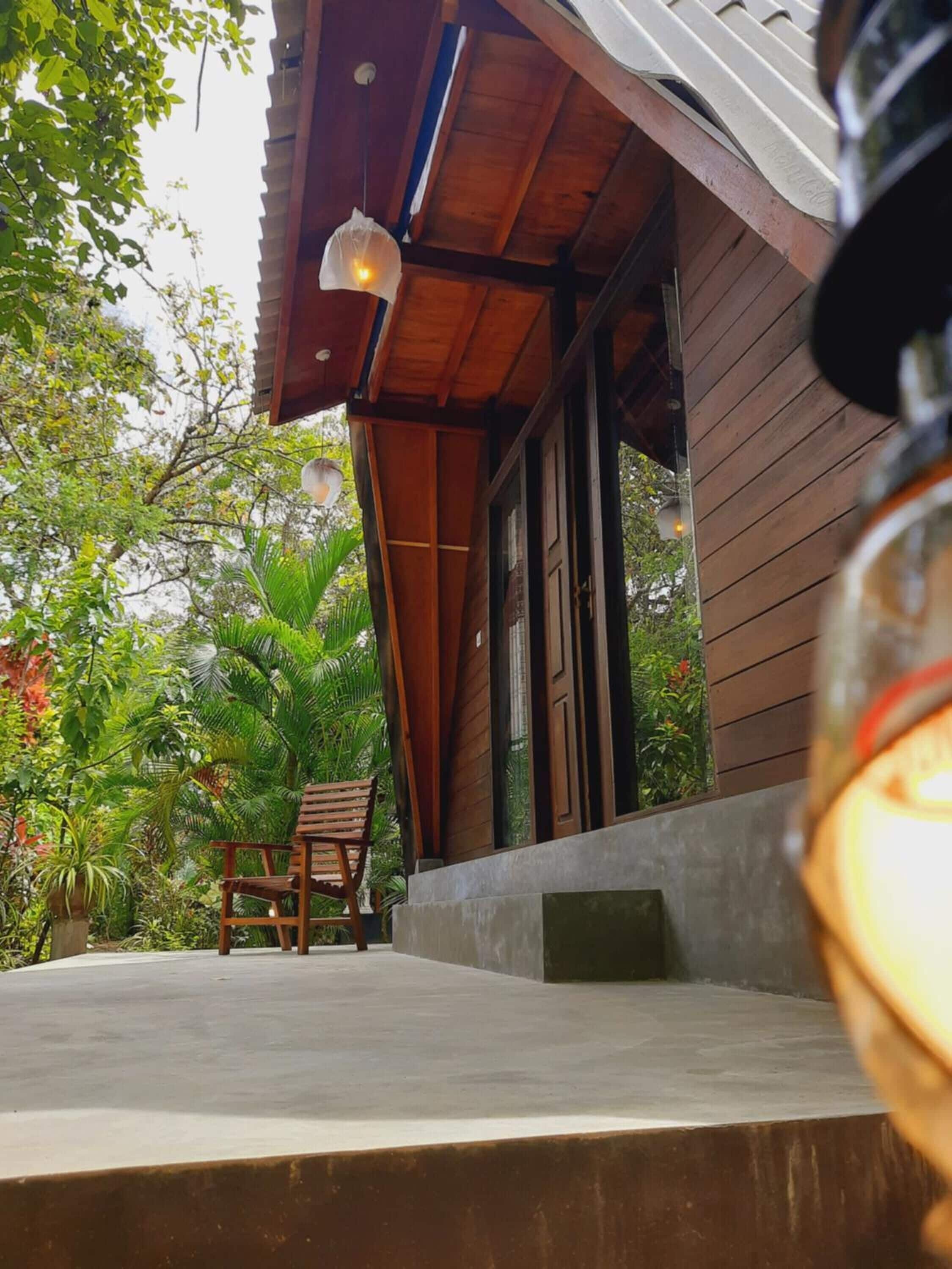 Un bâtiment en bois doté d’un porche couvert, d’un luminaire suspendu et d’une chaise.