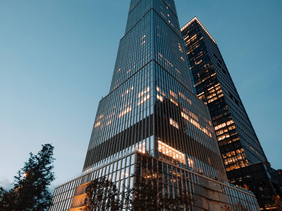 Un edificio alto con fachada de vidrio moderna y una entrada destacada en esquina.