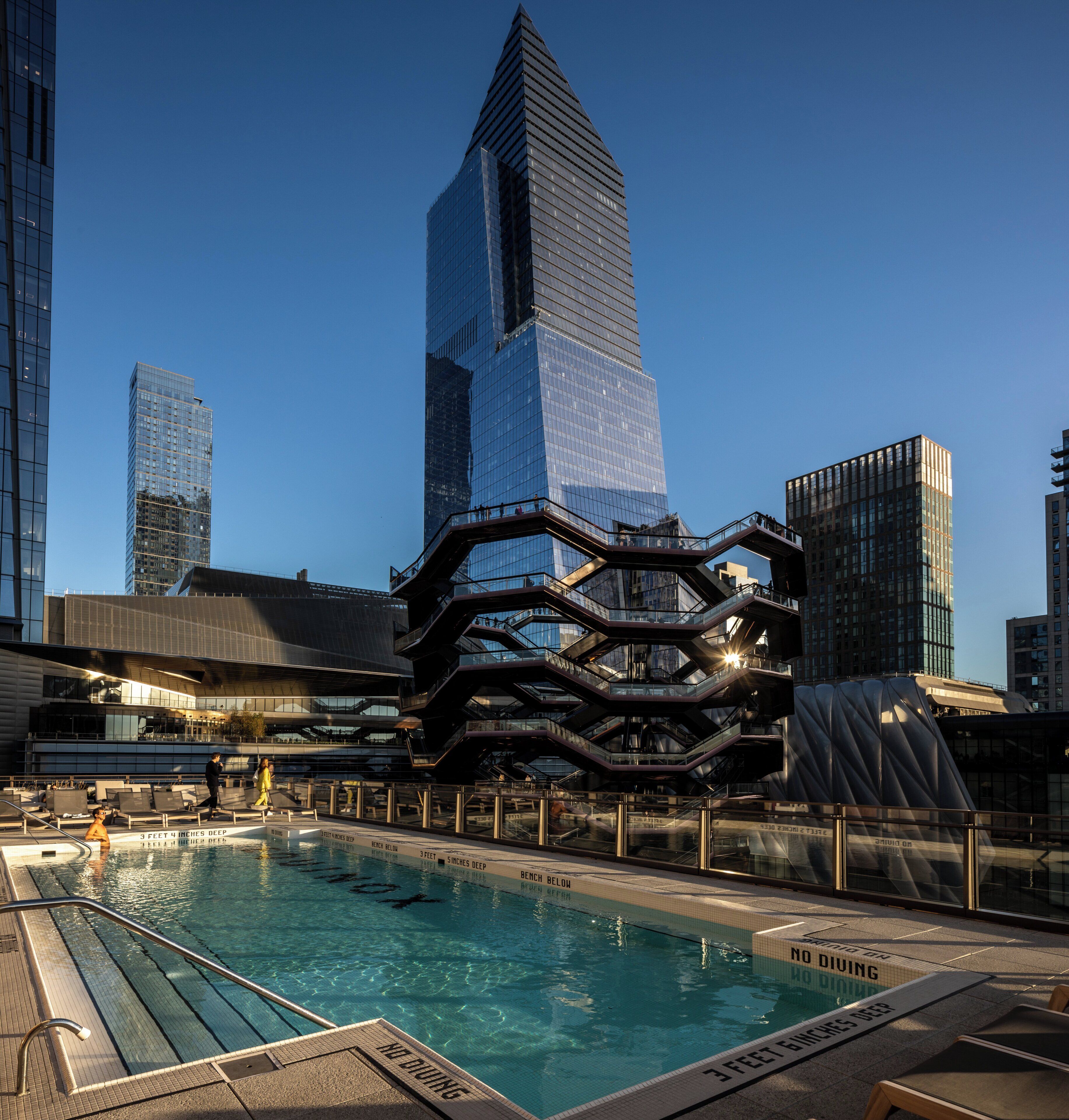 A modern building with a unique architectural design, a swimming pool, and a clear blue sky.