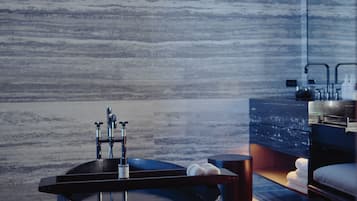 A modern bathroom with a large, dark, bowl-shaped bathtub, a visible faucet, and a wooden floor.