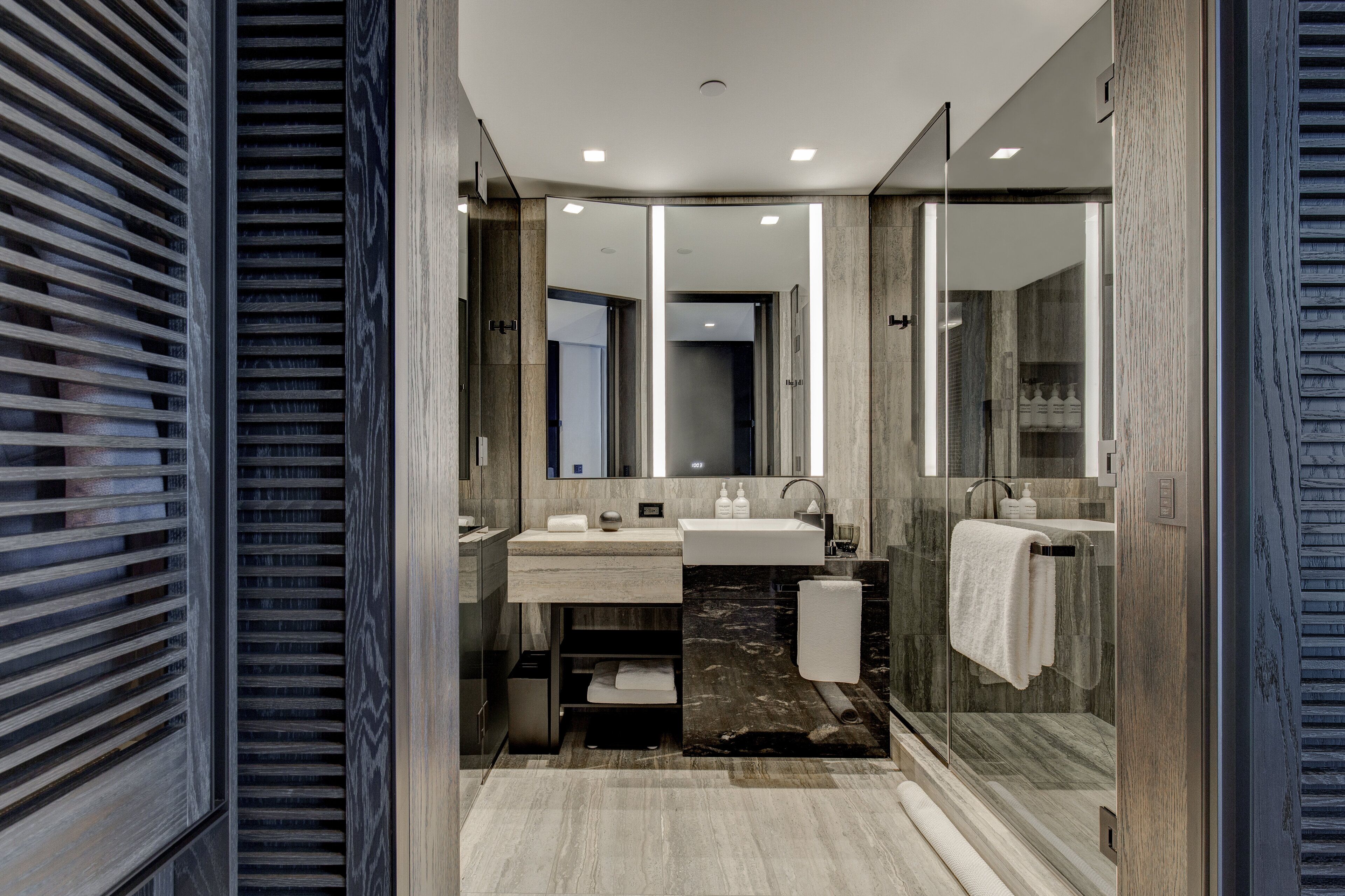 Une salle de bain moderne avec une douche à parois de verre, un meuble-lavabo avec un miroir et un évier.