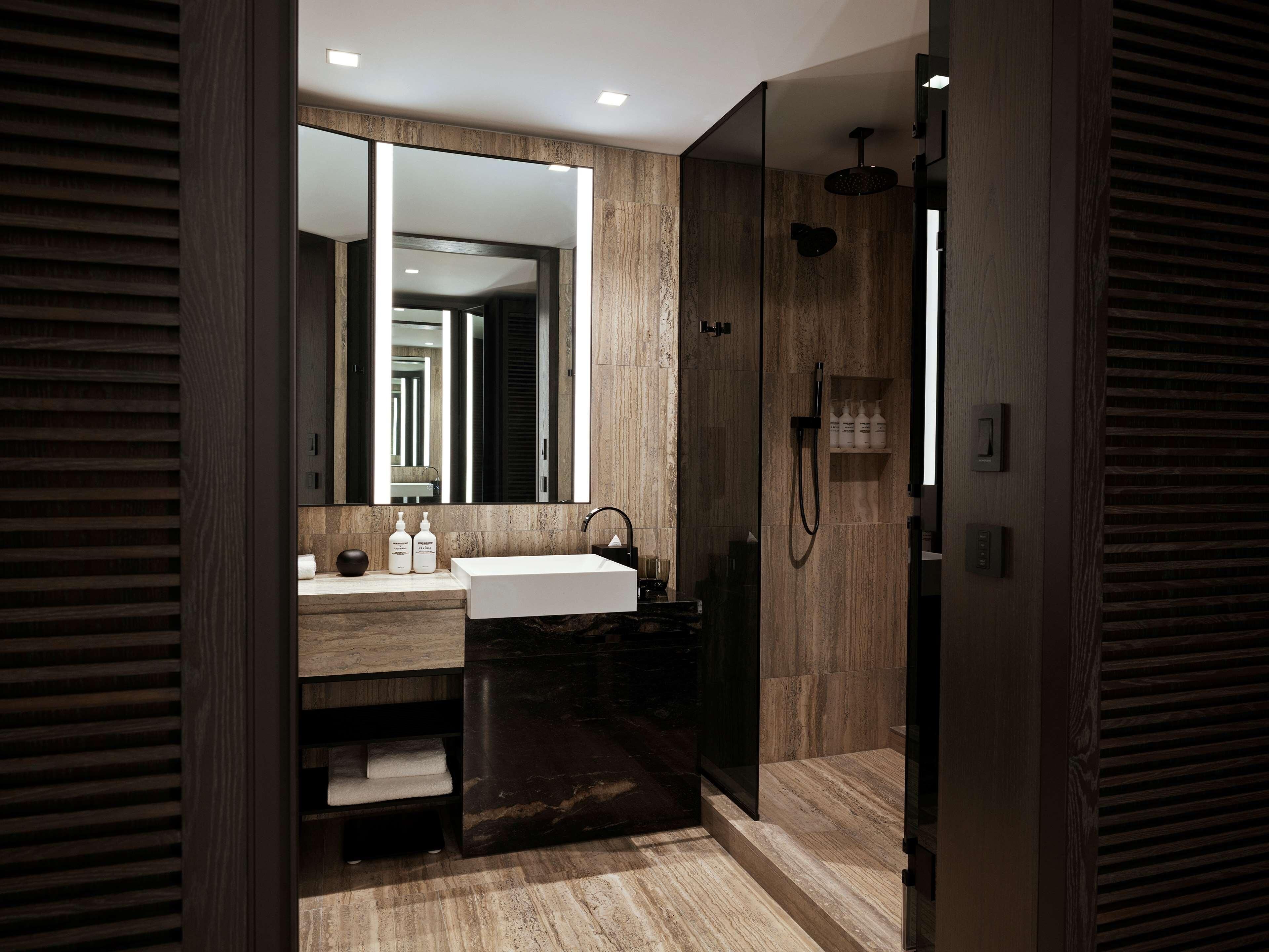 Een moderne badkamer met een grote spiegel, een wastafel, een douche en een badmeubel met opbergruimte.