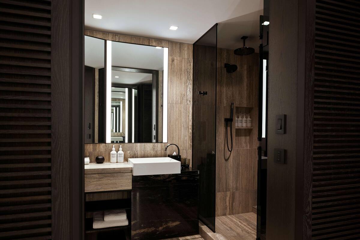 Un bany modern amb un mirall gran, un lavabo, una dutxa i un moble de tocador amb espais d'emmagatzematge.