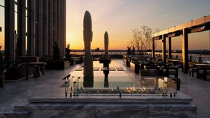 Terraço no telhado com lareira, espaços para sentar e vista para o pôr do sol.