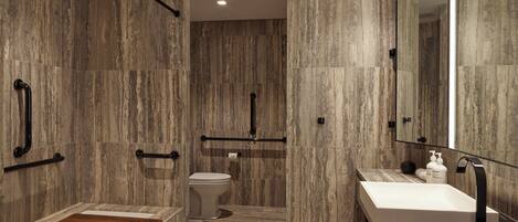 A modern bathroom with a marble floor, a wooden vanity, a white sink, and a large mirror.