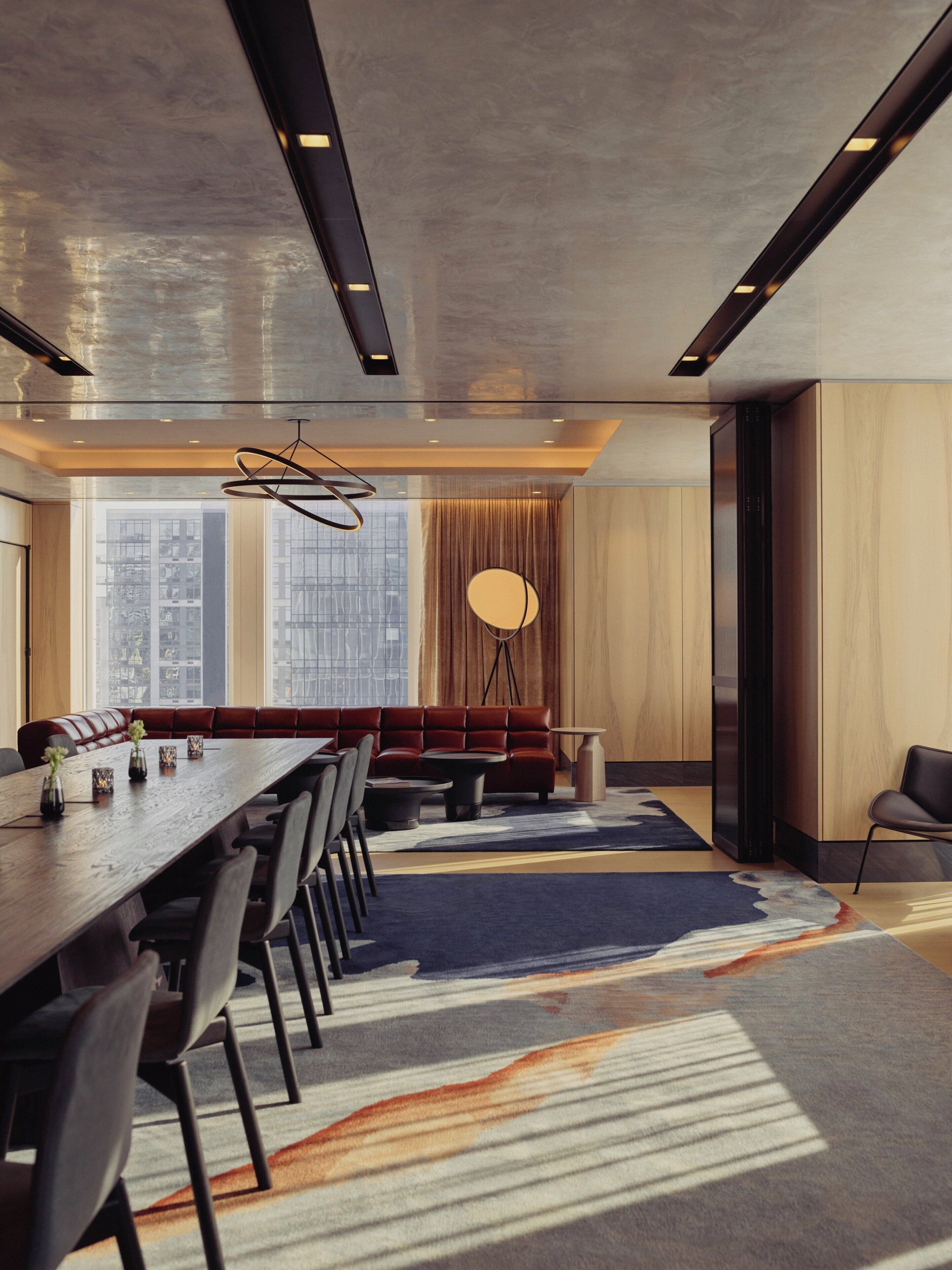 Un espace de repas moderne comprenant une longue table, des chaises, un canapé et un lampadaire.