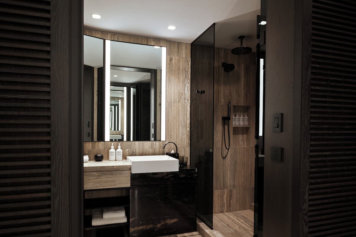 Un bany modern amb un mirall gran, un lavabo i una zona de dutxa.