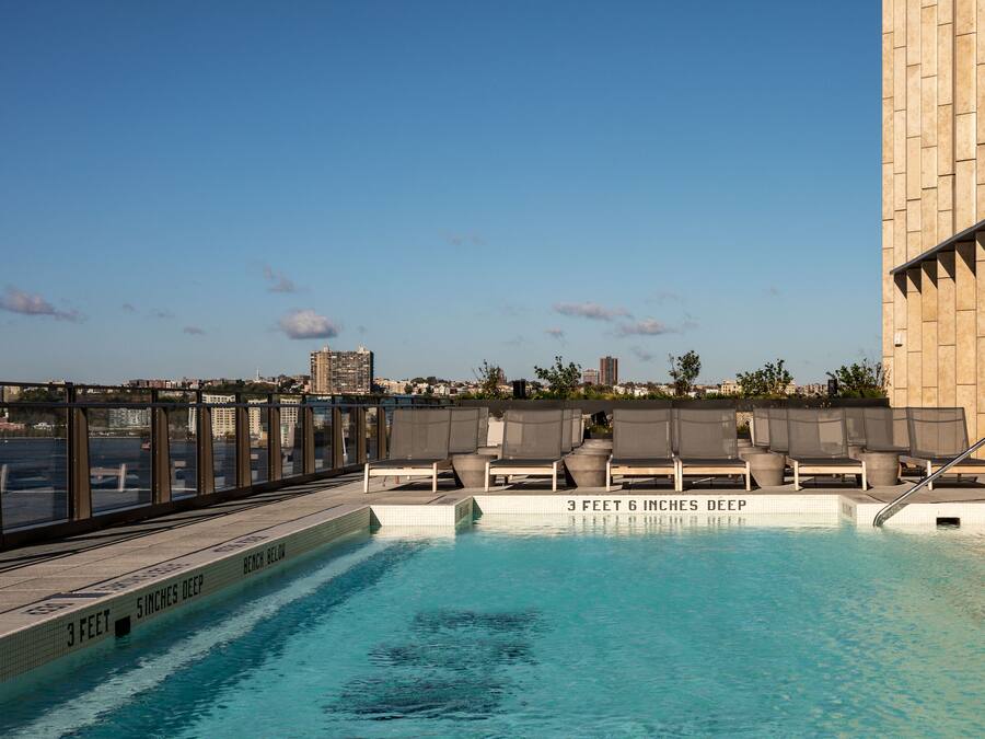 Una piscina sul tetto con acqua cristallina, sedie a sdraio e vista sullo skyline della città.