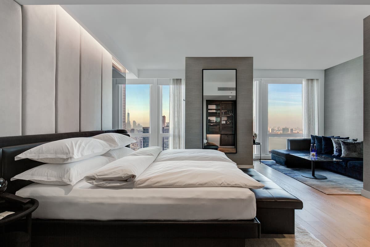 Habitació d'hotel moderna amb un llit gran, zona de seients i vista a la ciutat.