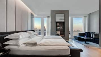 A modern hotel room with a large bed, a seating area, and a city view.