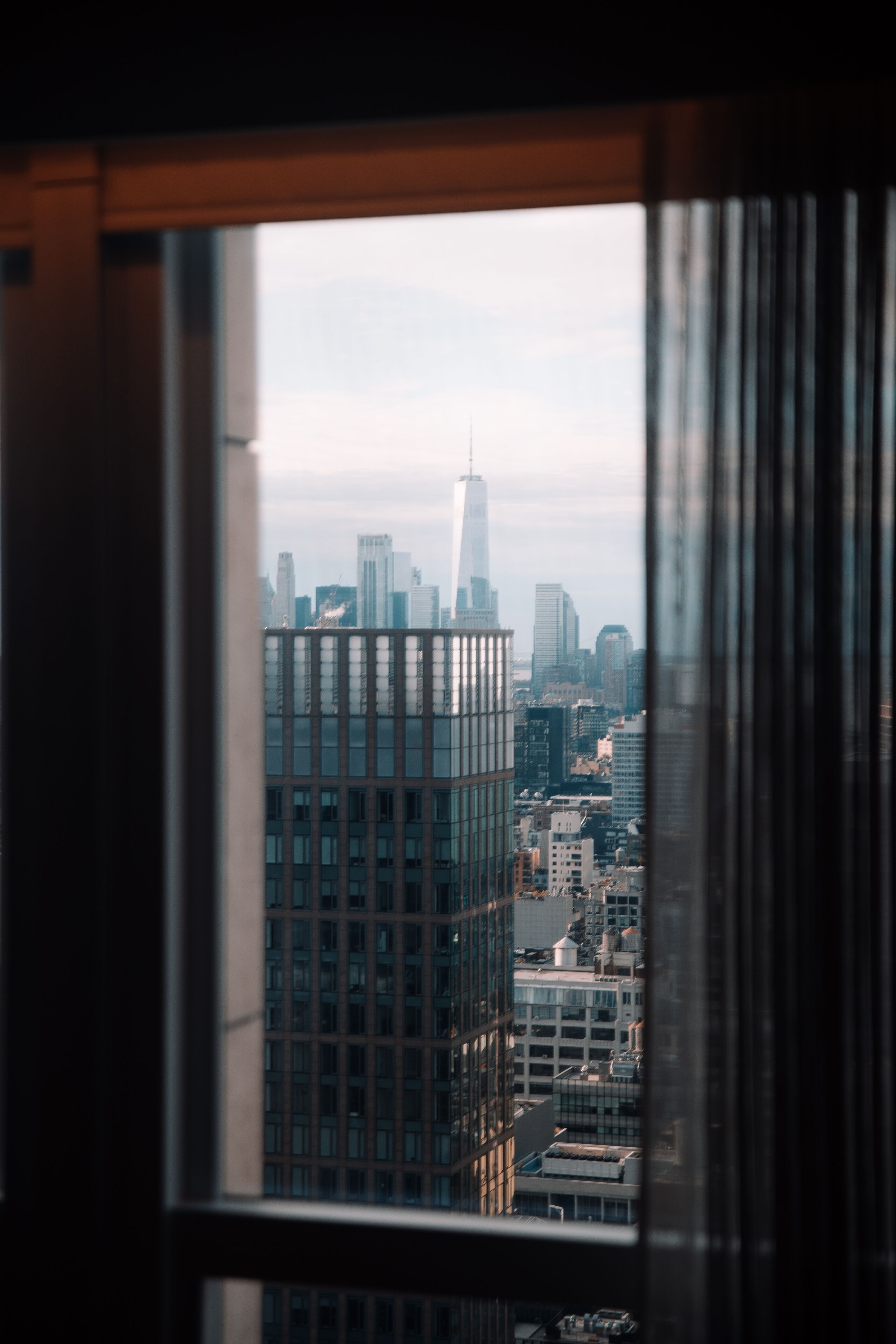 A view of a cityscape through a window with a building in the foreground.