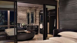 Quarto moderno com cama grande, banheira e vista para a cidade.