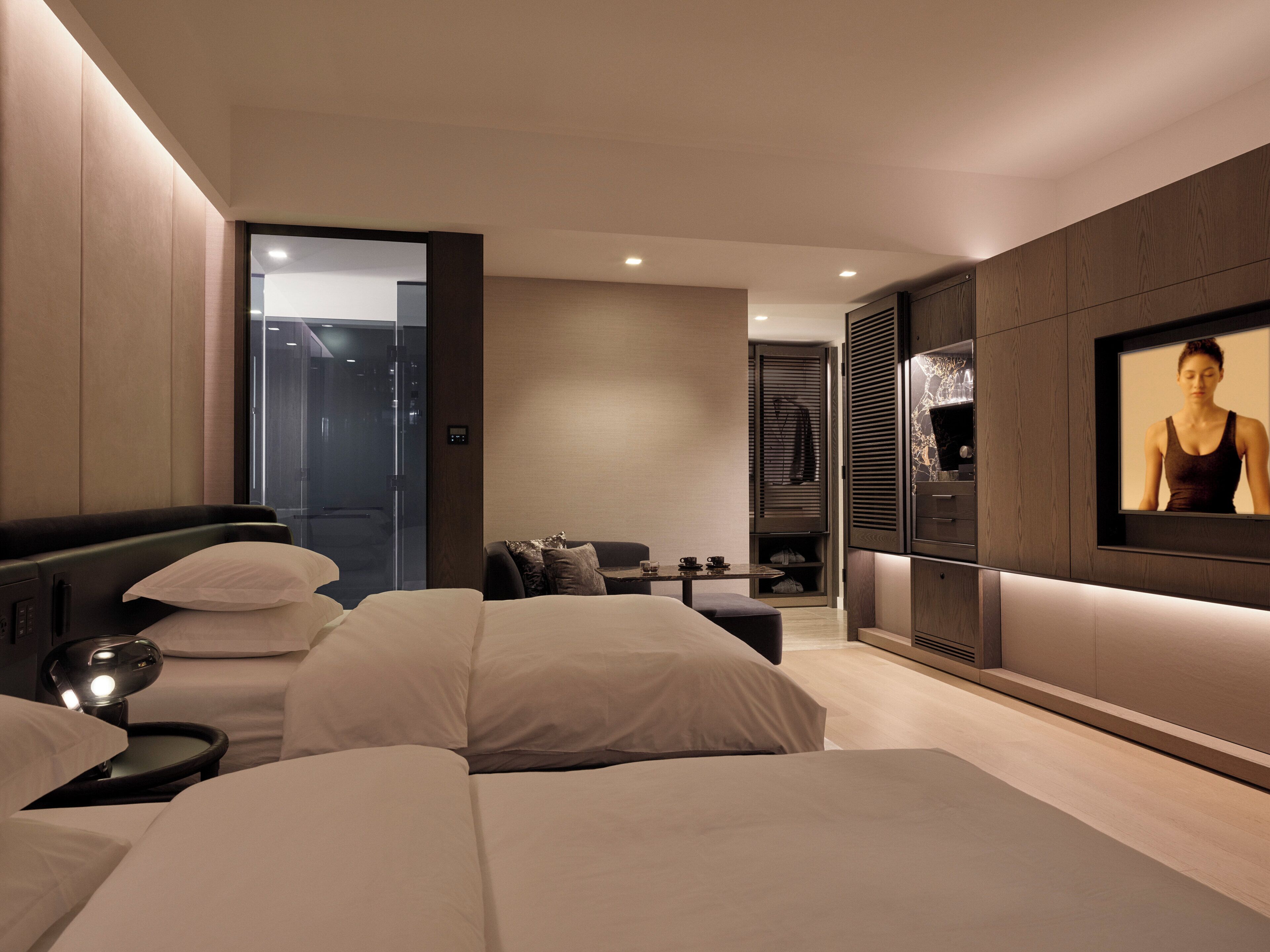 A modern bedroom with a large bed, bedside tables, a TV, and a walk-in closet.