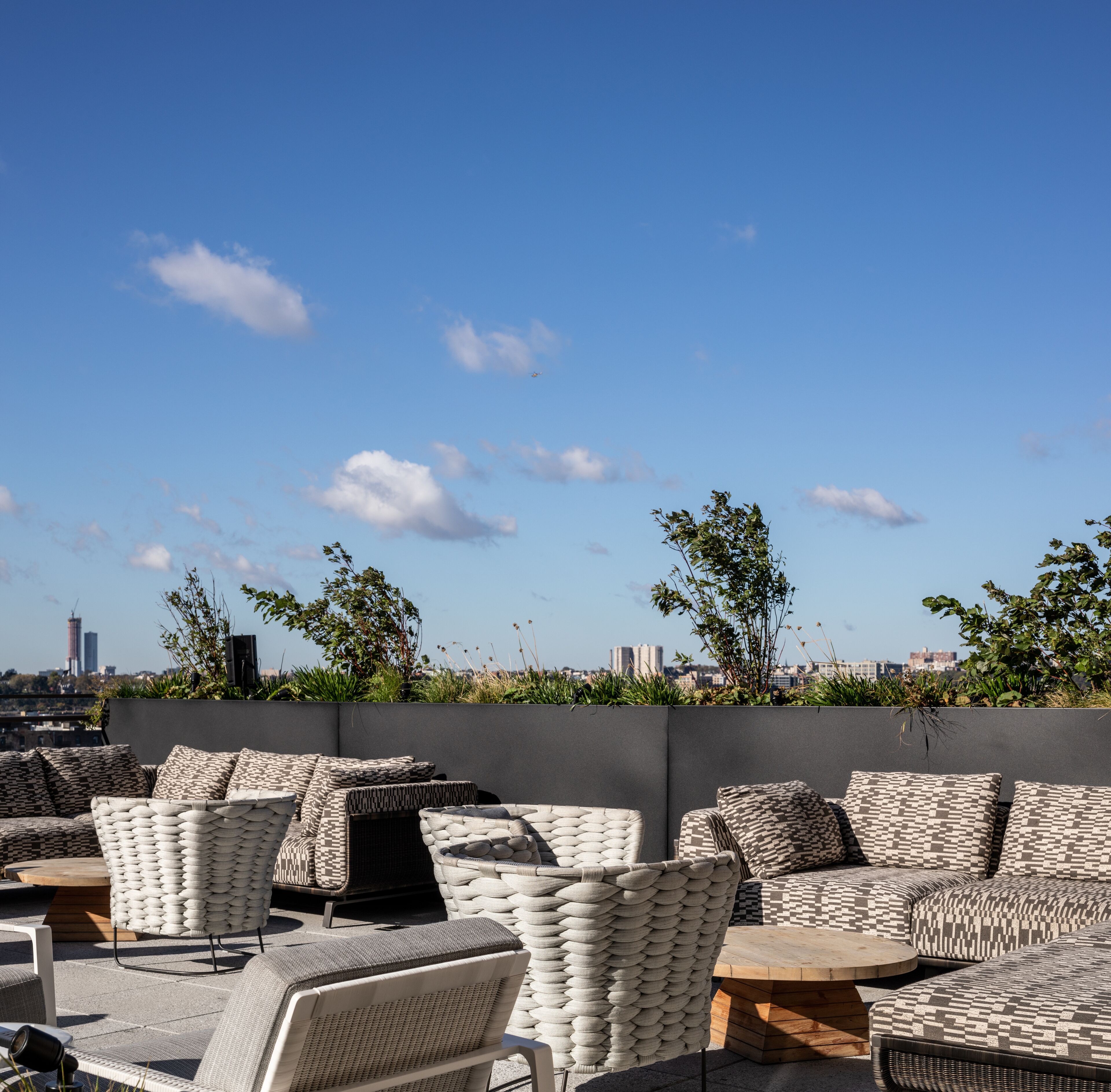 An outdoor seating area with wicker furniture and a view of the city skyline.