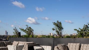 An outdoor seating area with wicker furniture and a view of the city skyline.