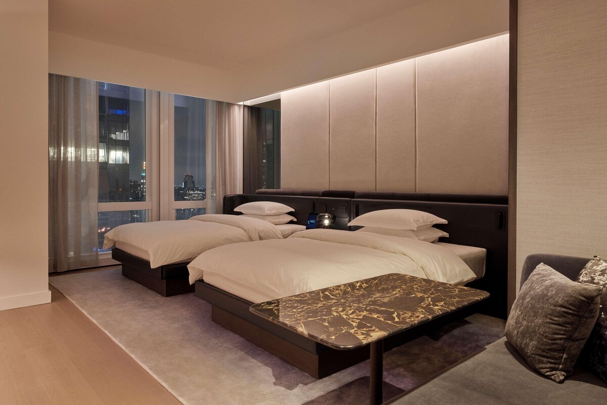 Une chambre d’hôtel moderne avec un grand lit, une petite table et une vue sur la ville.