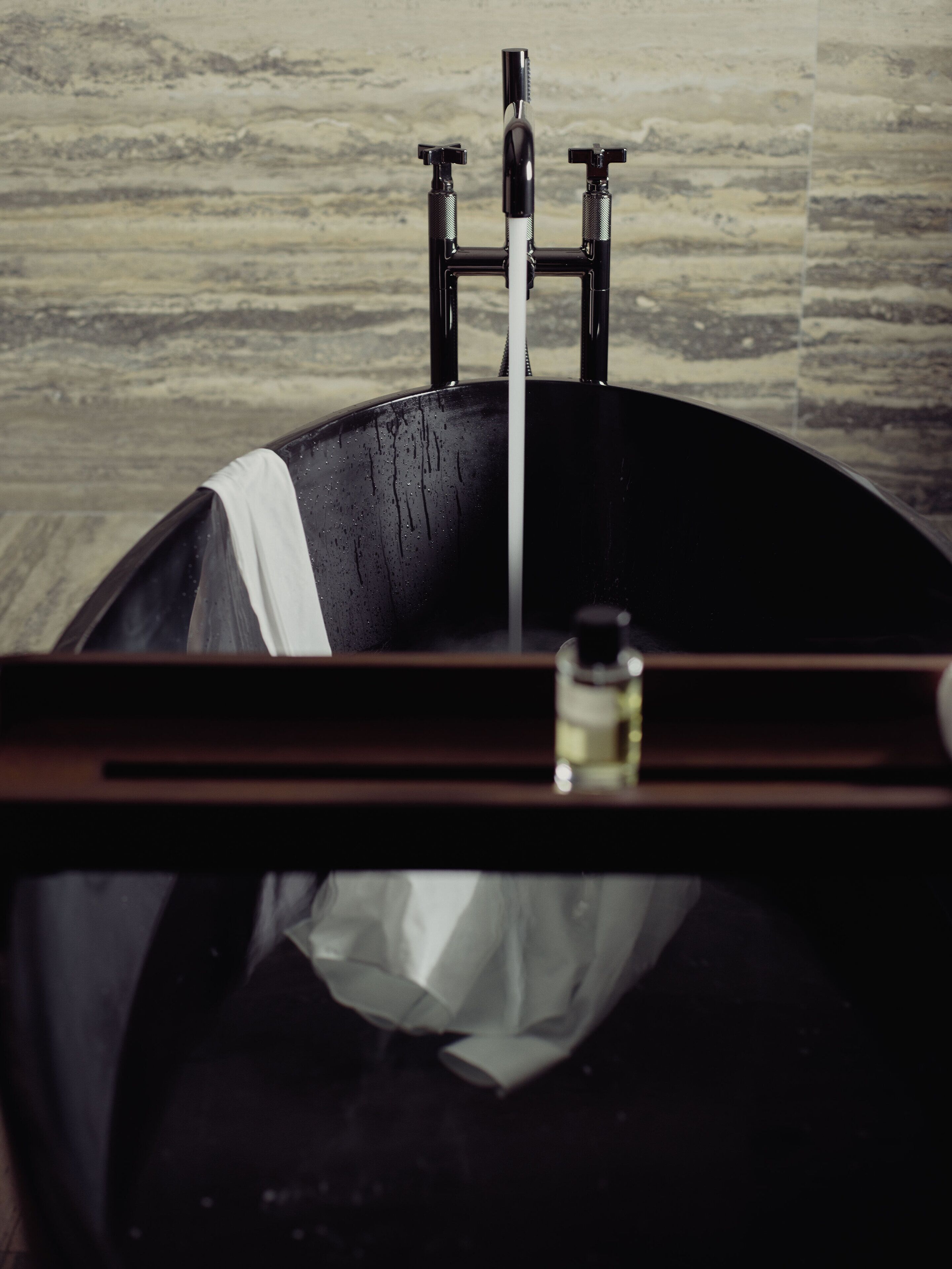 A bathtub with a faucet and a bottle of soap.
