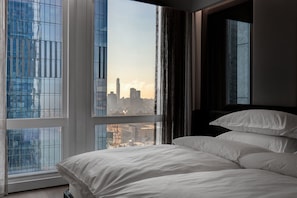 A hotel room with a large window, a bed, and a view of a city skyline. - Equinox Hotel New York (New York)