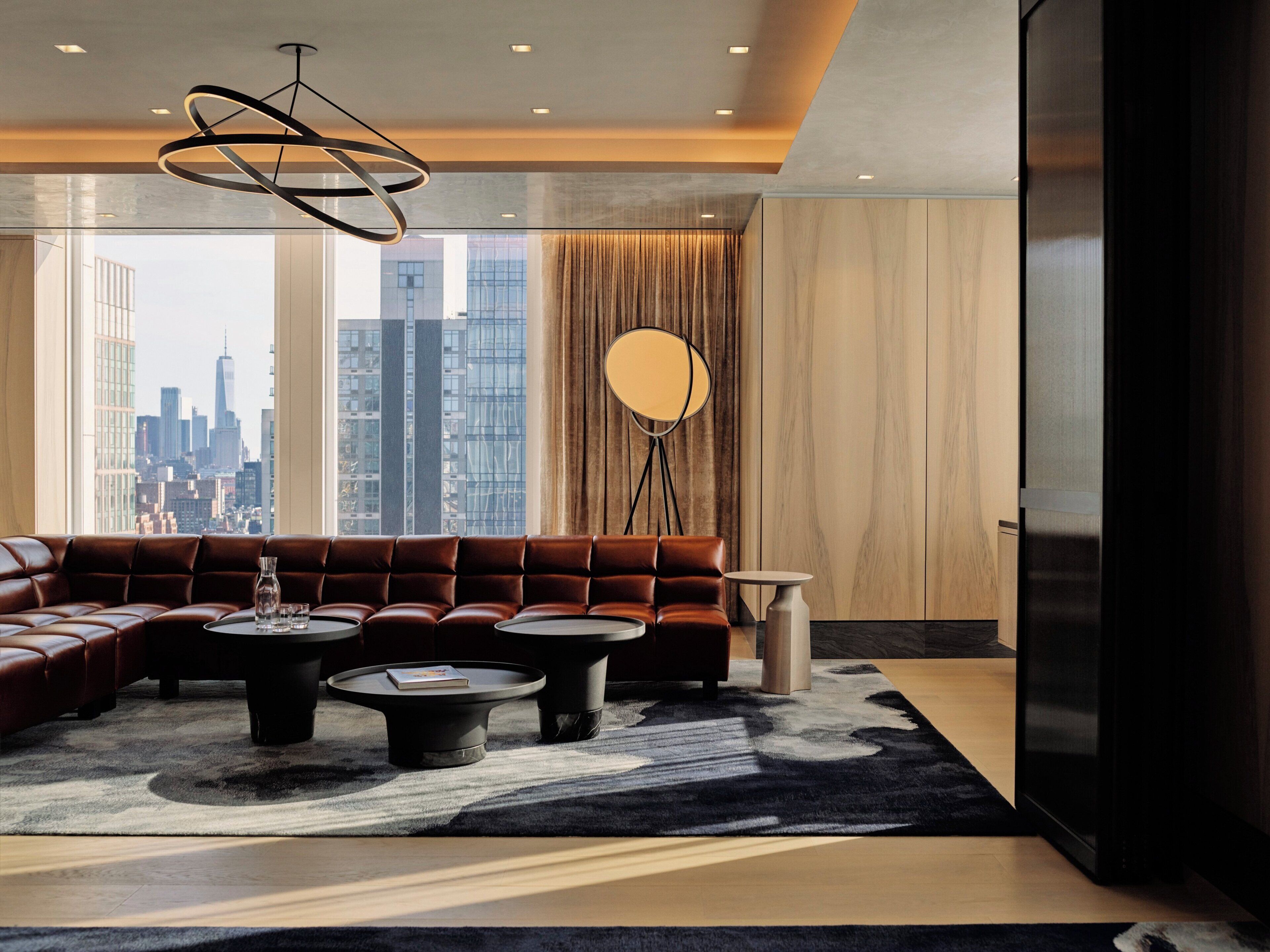 Een moderne woonkamer met een hoekbank, twee ronde salontafels, een vloerlamp en uitzicht op de stad.