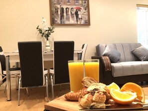 Een ontbijttafel met broodjes, sinaasappelschijfjes en een glas jus d'orange.