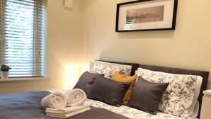 A neatly made bed with a rolled white towel, a mustard-colored throw blanket, and floral-patterned bedding. - Park View 2 Bedroom By Creatick (Maidenhead)