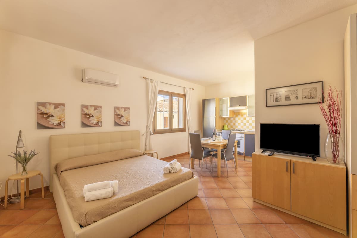 Una habitación de hotel con cama, escritorio, televisión y obras de arte en las paredes.