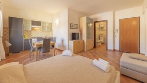 A hotel room with a bed, a desk, a chair, a kitchenette, and a bathroom. - Residence Cristal Blu (Santa Teresa di Gallura)