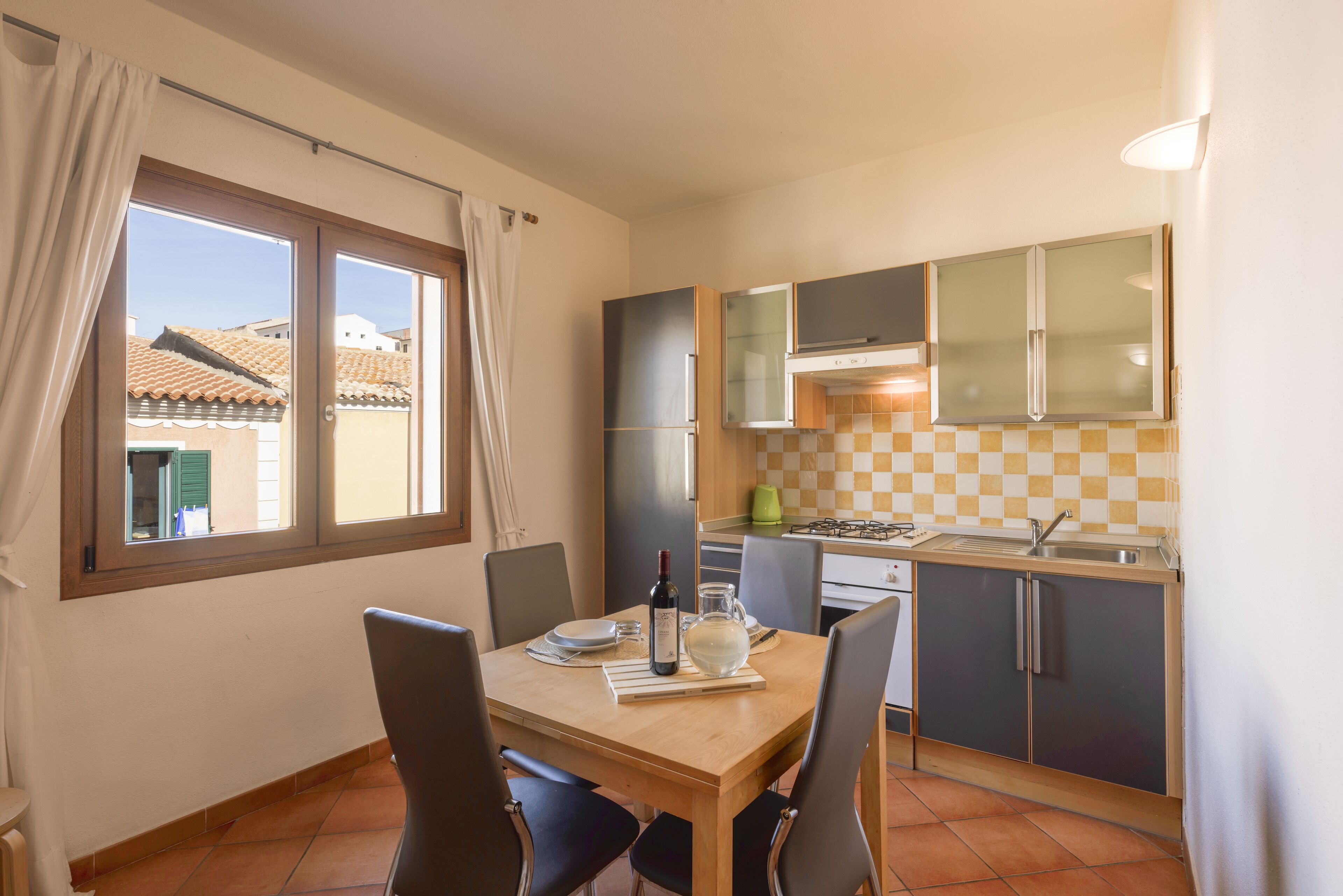 A compact kitchen with a dining table, chairs, and a view of the outside through a window.