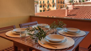A table set with plates, glasses, and cutlery on a wooden table with a view of buildings in the background. - Residence Cristal Blu (Santa Teresa di Gallura)