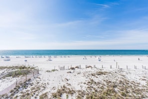Une vaste plage de sable fin, sous un ciel bleu et dégagé.