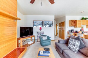 Relax in this inviting living space with a flat-screen TV, comfortable seating, and a bookshelf.