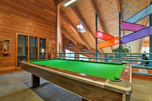 Enjoy a game of pool in this well-lit room with a shower area nearby.