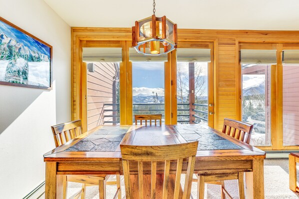 Enjoy meals with a view of the surrounding mountains from this dining area with a large window and wooden table.